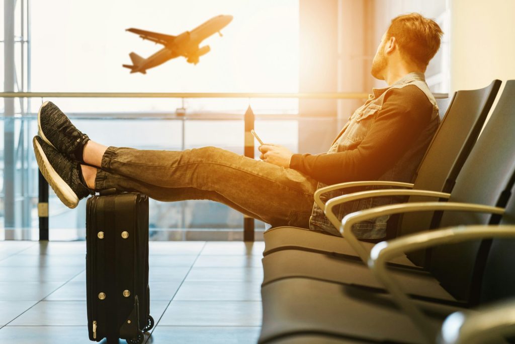 Hombre sentado en una silla con los pies sobre el equipaje mirando el avión